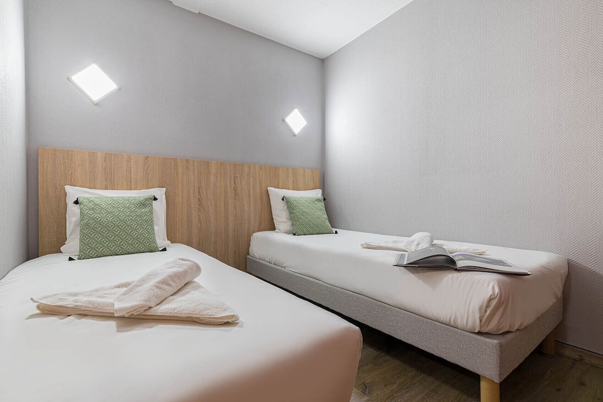 A hotel room with two beds, each with a pillow and a folded towel.