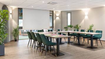 A conference room with a long table, green chairs, and potted plants.