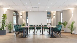 A conference room with a long table, green chairs, and potted plants. - Hotel l'Abri (Blavozy)