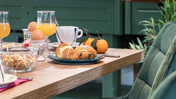 A breakfast table with croissants, oranges, and a coffee cup. - Hotel l'Abri (Blavozy)