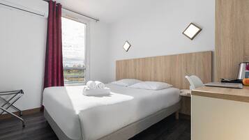 Quarto de hotel com cama, escrivaninha e vista para o exterior.