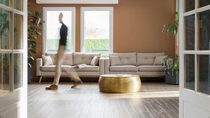 A modern living room with a beige sofa, a round gold coffee table, and large windows. - Hotel l'Abri (Blavozy)