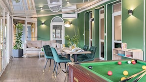 A modern indoor pool area with a pool table, green walls, and a seating area with a sofa and chairs. - Hotel l'Abri (Blavozy)