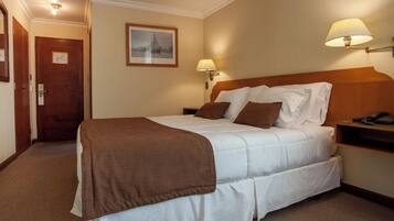 Ein Hotelzimmer mit Bett, Nachttisch, Lampe und Tür.