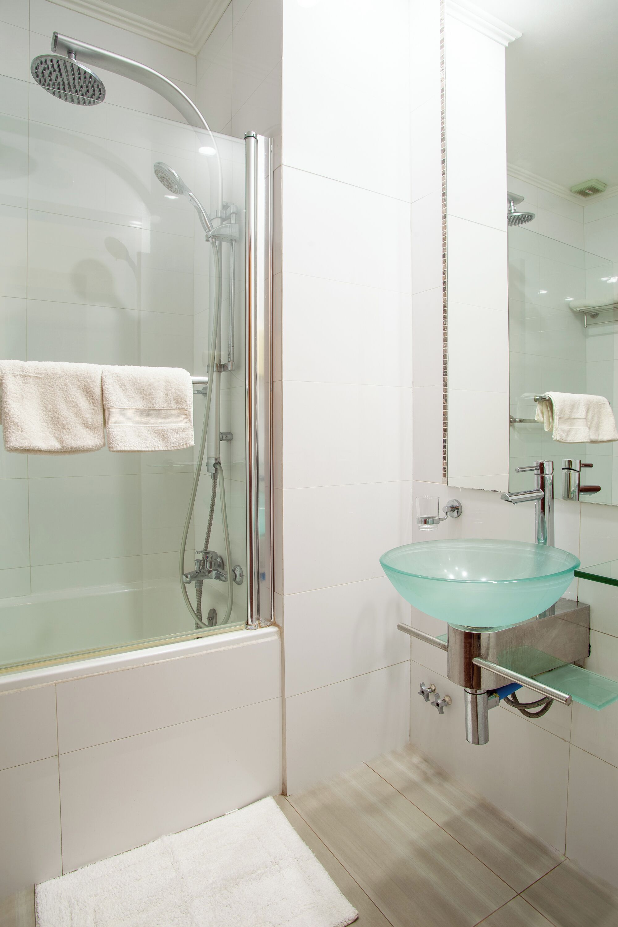 Un bagno moderno con cabina doccia in vetro, lavabo in vetro e un grande specchio.