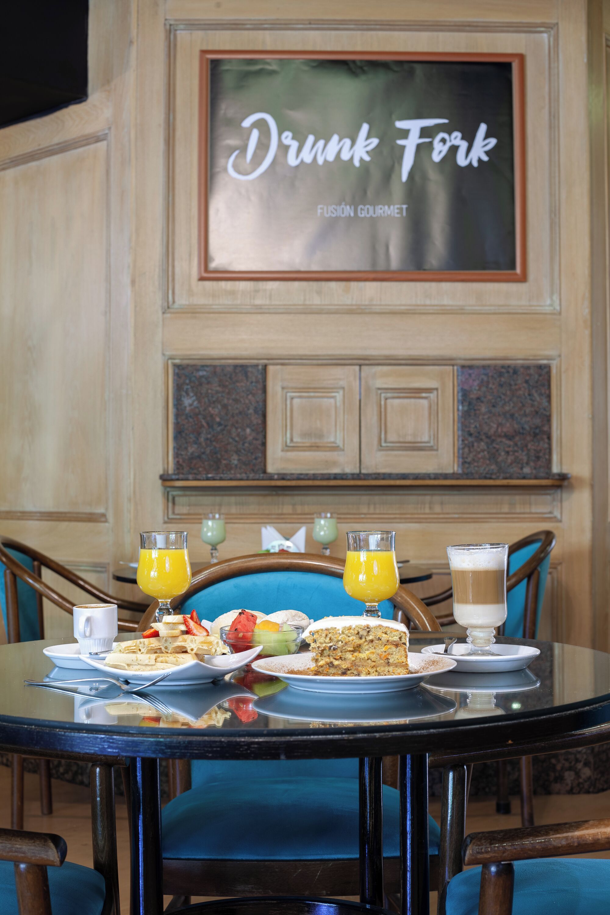 Una mesa de comedor con alimentos para el desayuno, dos vasos de jugo de naranja y un pastel.