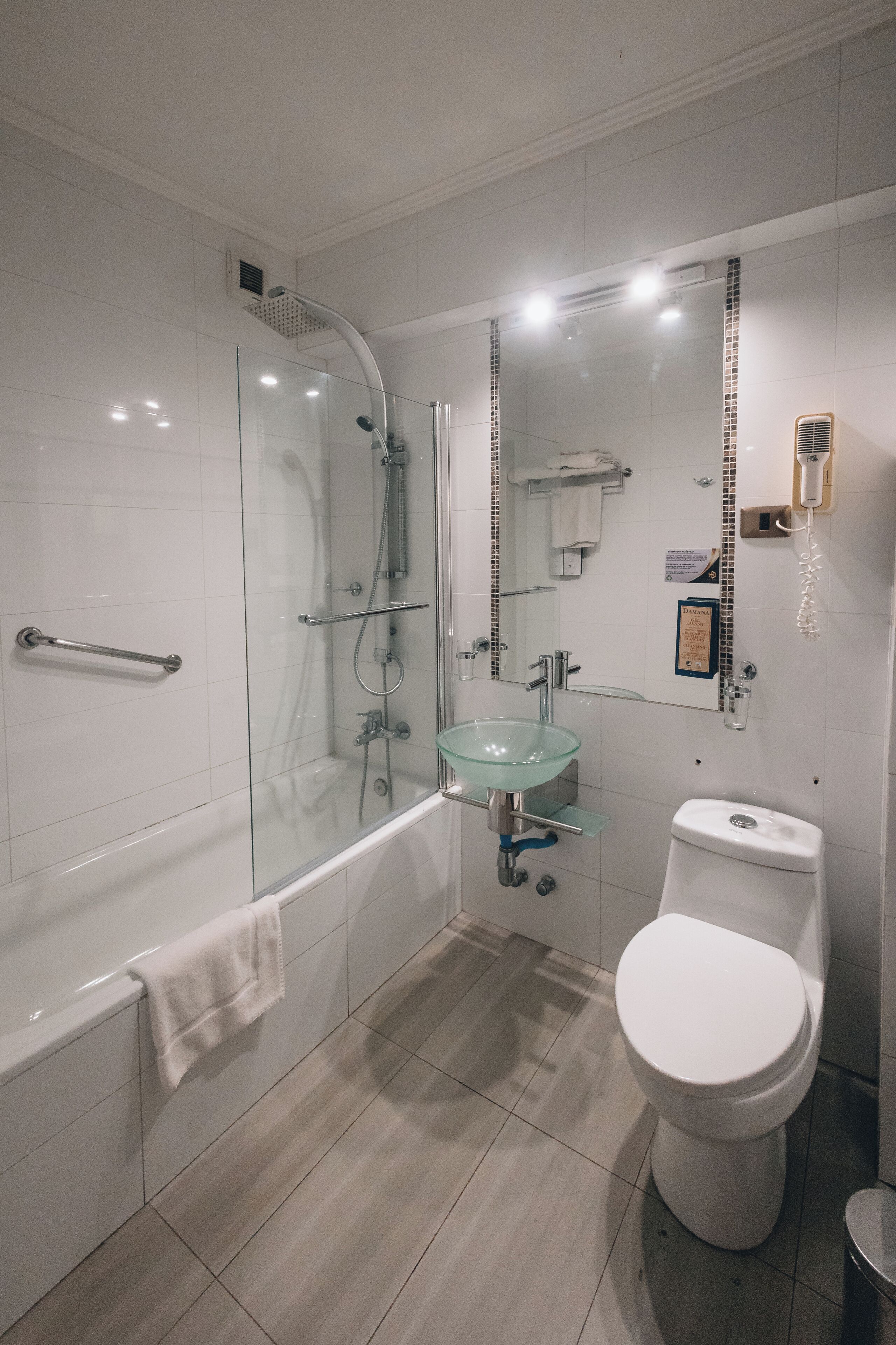 Ein modernes Badezimmer mit einer Duschkabine, einem Waschbecken aus Glas, einer Toilette und einer Badewanne.