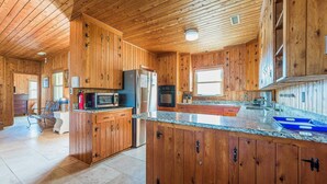 Cocina amplia con armarios de madera, encimera de granito y electrodomésticos modernos.