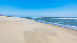 Una playa con cielo despejado y mar tranquilo.