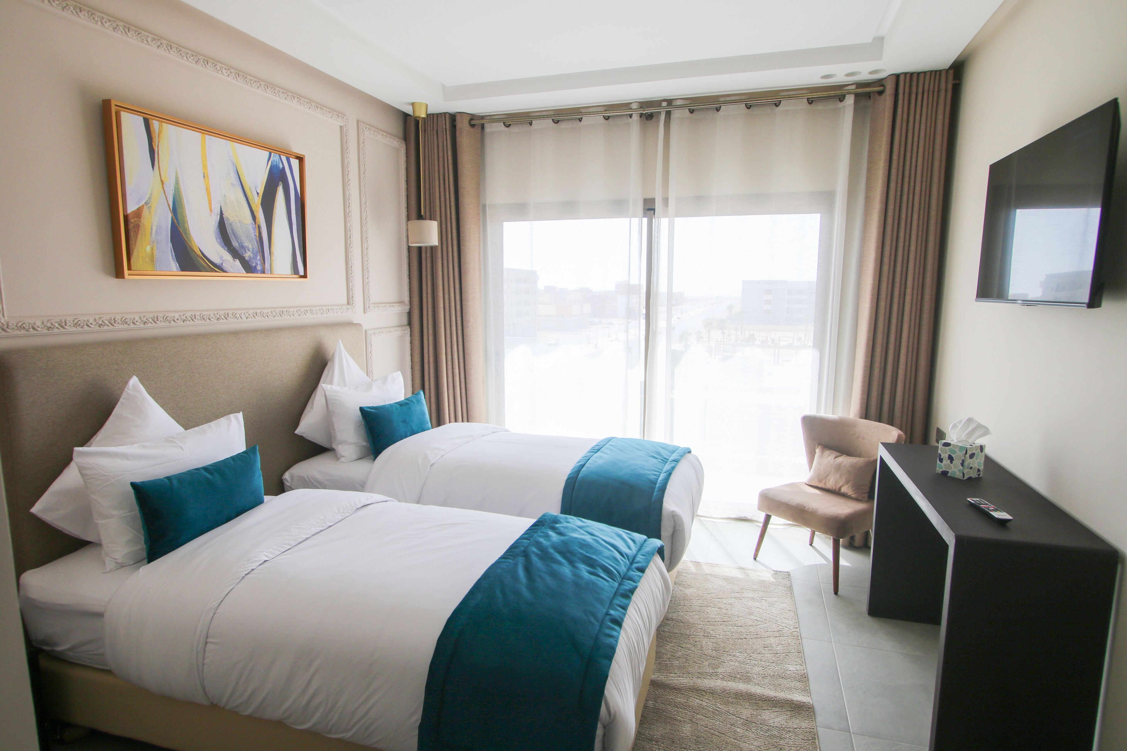 Habitación de hotel con dos camas, televisión y vistas de la ciudad.