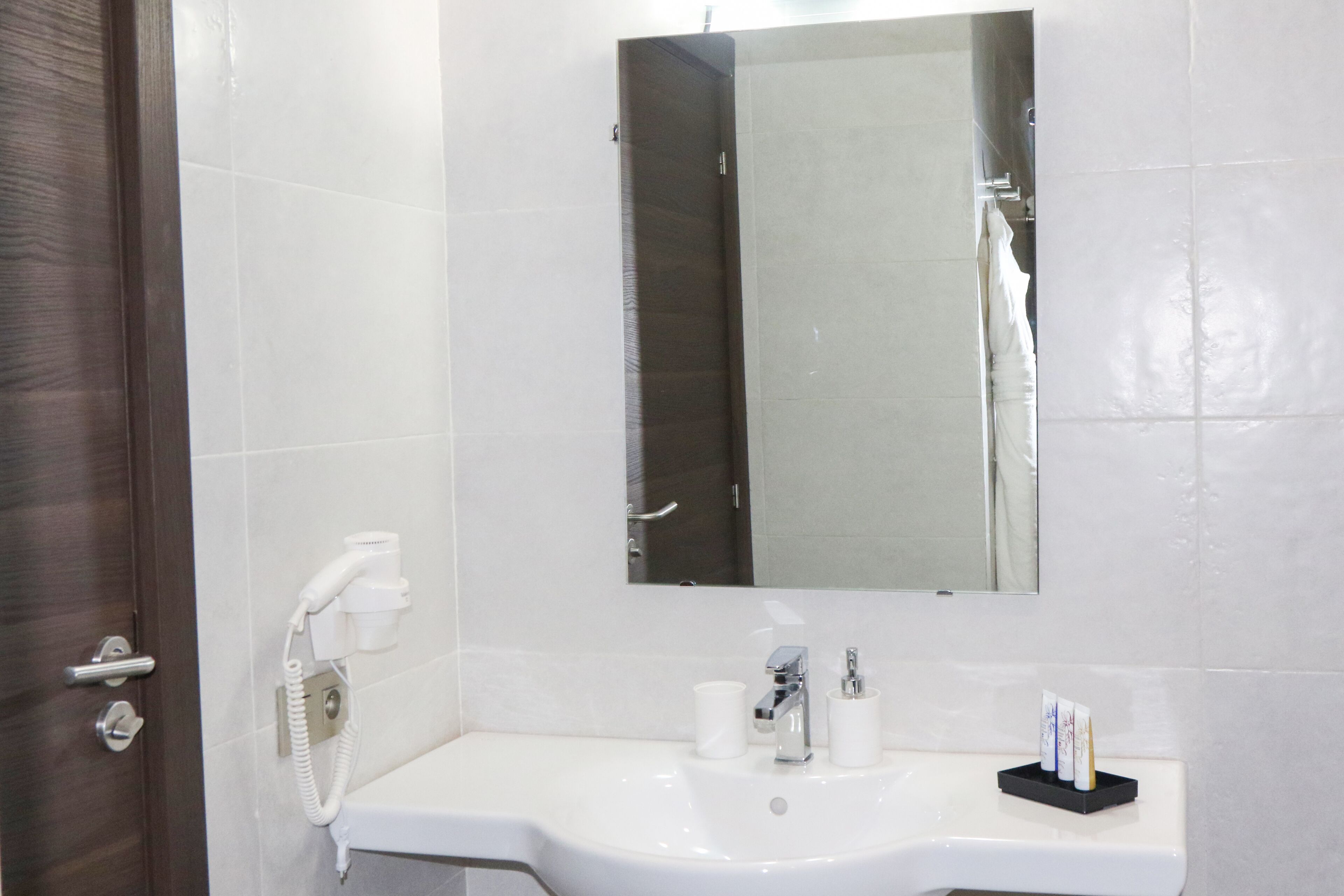 A bathroom with a white sink, a mirror, a hairdryer, and a towel rack.