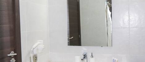 A bathroom with a white sink, a mirror, a hairdryer, and a towel rack.