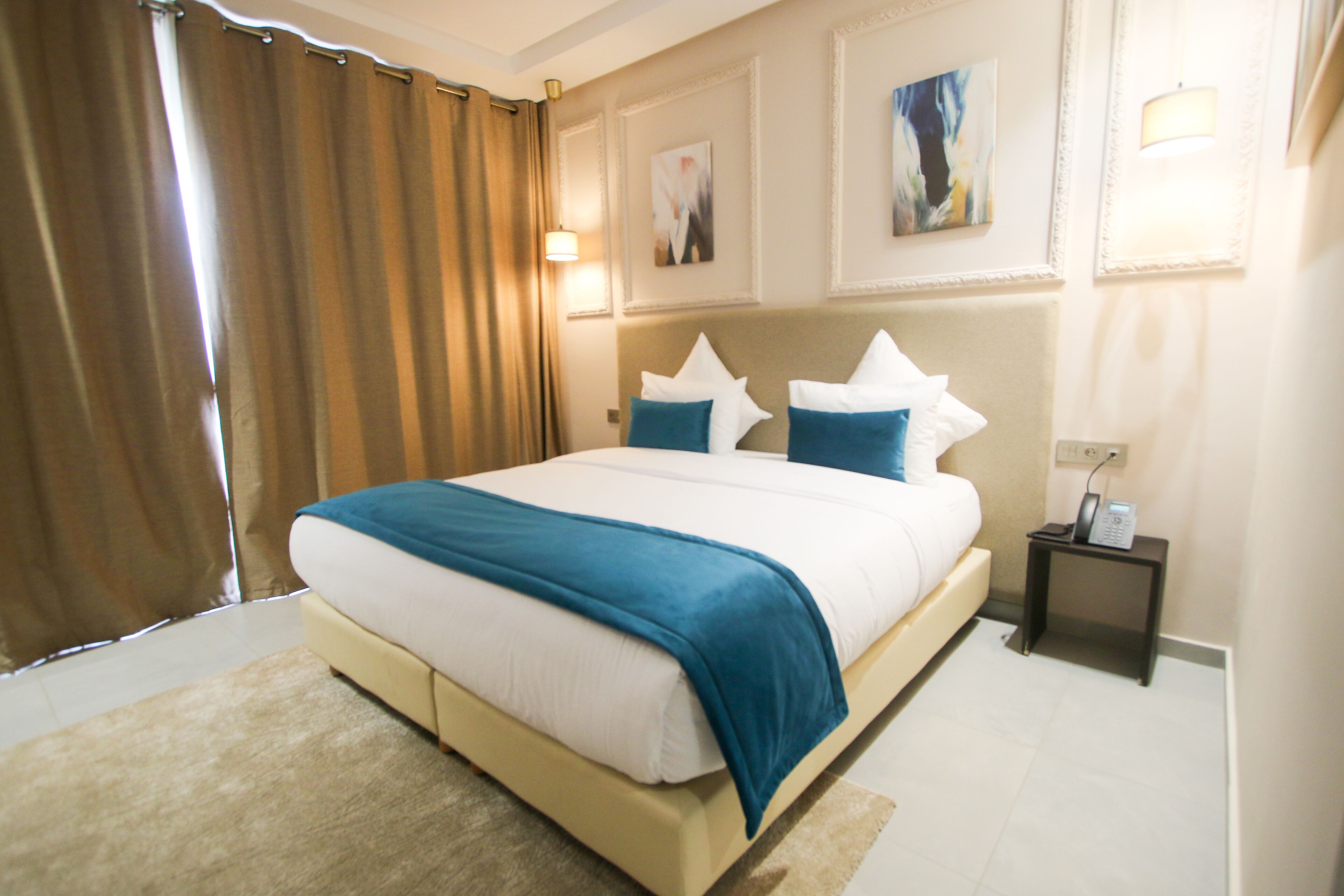 Une chambre d’hôtel avec un grand lit, une table de chevet, une lampe et un tableau au mur.