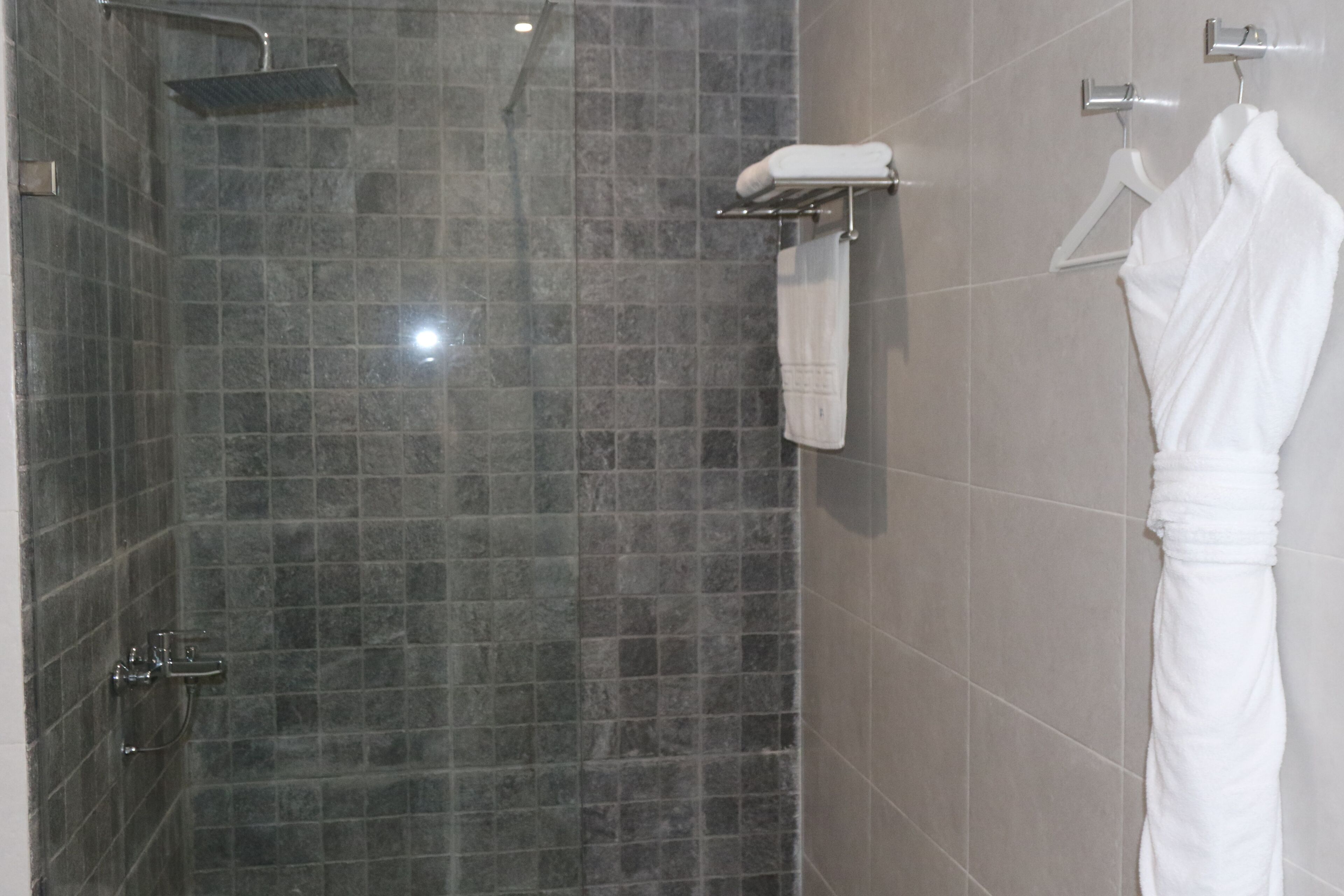 A modern bathroom with a shower, tiled walls, and a towel rack.