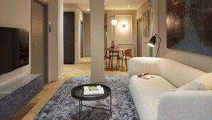 A modern living room with a flat-screen TV, a white sofa, a coffee table, and a dining area with a table and chairs. - Azoka Suite by FeelFree Rentals (Donostia)
