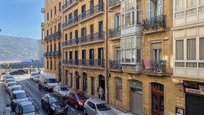 A street view with parked cars and a building with multiple balconies and windows. - Azoka Suite by FeelFree Rentals (Donostia)