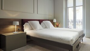 A modern hotel room with a large bed, two bedside tables, a nightstand, and a view of the outside balcony. - Azoka Suite by FeelFree Rentals (Donostia)