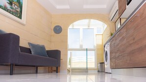 Una sala de estar moderna con un sofá, un reloj y vistas al exterior.