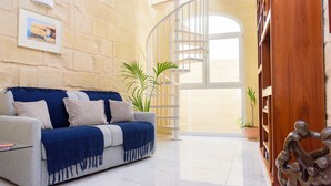 Una sala moderna con un sofá, una escalera en espiral y una estantería de madera.