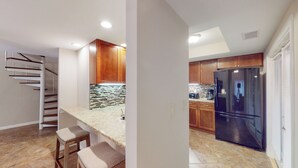 Una cocina moderna con armarios de madera, un refrigerador negro y un salpicadero de azulejos.
