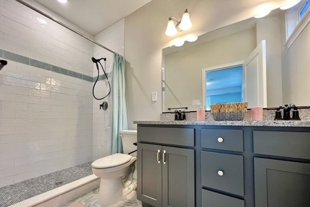 Une salle de bain équipée d’une douche, de toilettes et d’un meuble-lavabo avec des placards et un miroir.