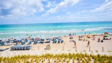 Na praia, espreguiçadeiras, guarda-sóis, toalhas de praia