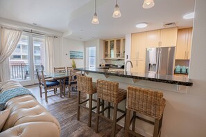 A modern kitchen with a central island, wooden cabinets, and a stainless steel refrigerator.