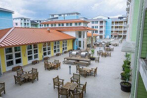 Une cour d’hôtel avec des espaces de repos en plein air, un coin barbecue et des bâtiments à plusieurs étages dotés de balcons.