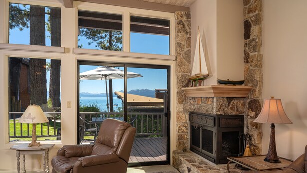 A cozy living room with a fireplace, leather recliner, and a view of the outdoors. - Star Harbor # 06 by Hauserman Rentals (Tahoe City)