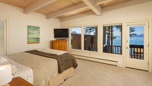 A bedroom with a bed, a TV, a painting, and a view of the sea through large windows. - Star Harbor # 06 by Hauserman Rentals (Tahoe City)