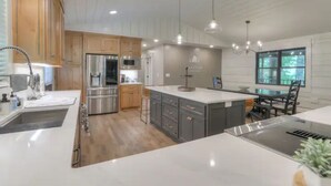 Une cuisine moderne avec des meubles en bois, des appareils électroménagers en acier inoxydable et des luminaires suspendus.