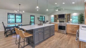 Une cuisine spacieuse dotée d’un grand îlot central, de meubles de rangement aux couleurs sombres et d’une cuisinière moderne.