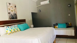 Hotelkamer met twee bedden, een schilderij aan de muur, een airconditioning en een nachtkastje met een lamp.
