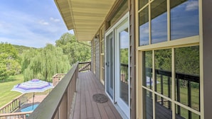 A wooden deck with a glass door leading to a lush green landscape. - 'Angler's Ridge' Waterfront Family Getaway! (Mammoth Spring)