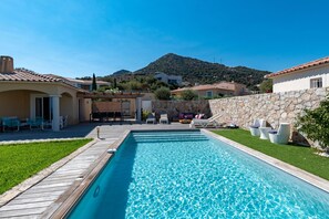 A swimming pool with a wooden deck, lounge chairs, and a stone wall. - Villa Acula - Five Bedroom Villa, Sleeps 10 (Monticello)