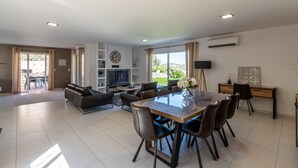 Una sala de estar moderna con comedor, televisor de pantalla plana y un ventanal grande.