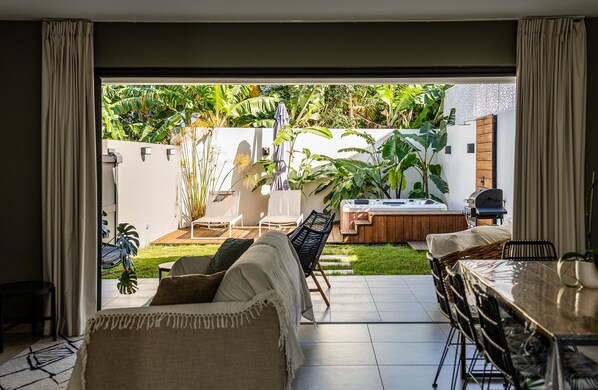 Un salon moderne avec une grande fenêtre, un canapé, une table à manger et un jacuzzi.