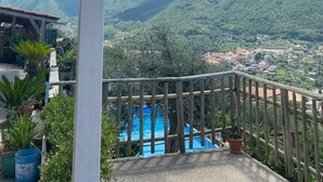 Ein Balkon mit Blick auf ein Gebirge und ein blaugraues Schwimmbecken.