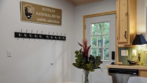 Ein Essbereich mit Tisch, Stühlen, einer Blumenvase, einem Garderobenhaken und einem Schild, das den Ort als Buffalo National River in Jasper, Arkansas, kennzeichnet.