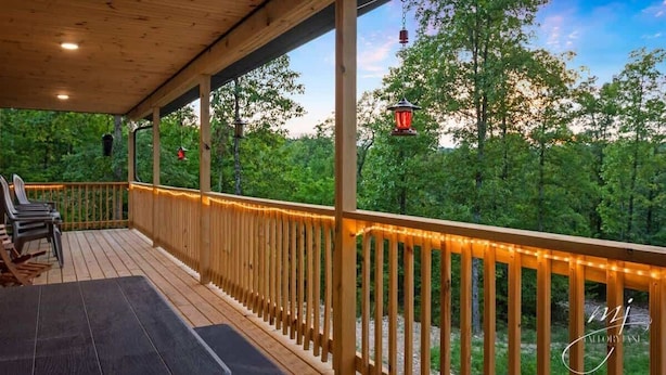 Eine Holzterrasse mit Geländer, Sitzgelegenheiten im Freien und Lichterketten.