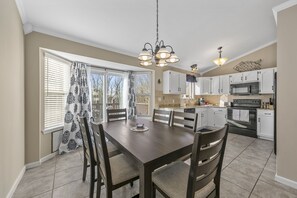 Una cocina moderna con armarios blancos, una mesa de comedor con sillas y una araña.