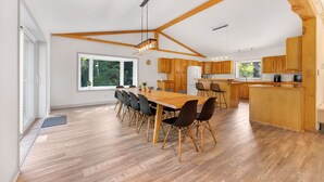 Une cuisine spacieuse dotée de meubles en bois, d’un grand îlot central et d’un coin repas avec une longue table et des chaises.
