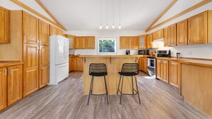 Une cuisine moderne avec des meubles en bois, un réfrigérateur blanc, un four encastré et une grande fenêtre.