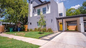 A modern two-story house with a garage, a well-maintained lawn, and a clear sky.