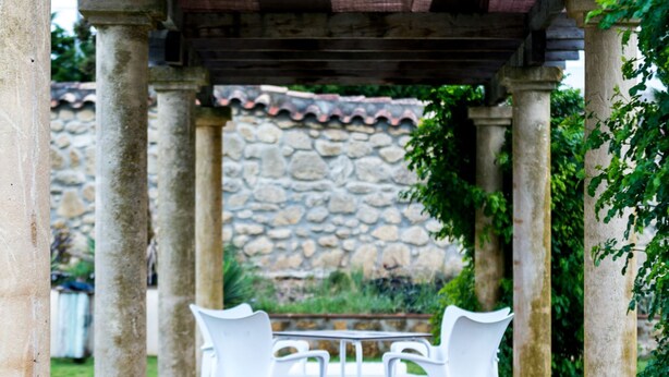 A covered outdoor seating area with stone columns and a stone wall in the background. - H. Doble Nómadas - One Bedroom Hotel, Sleeps 2 (Vejer de la Frontera)