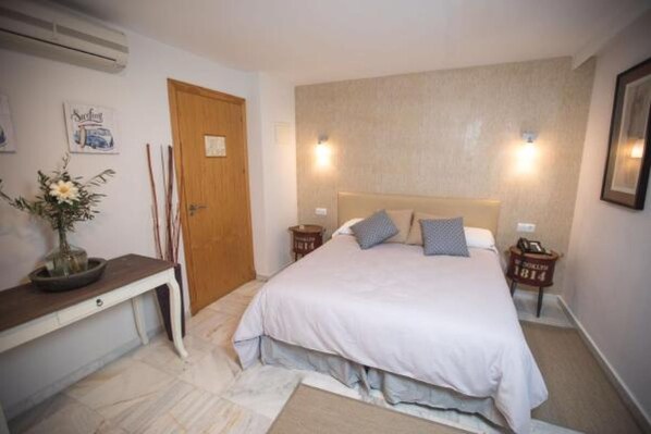 A bedroom with a bed, bedside tables, a desk, and a vase with flowers. - H. Doble Nómadas - One Bedroom Hotel, Sleeps 2 (Vejer de la Frontera)