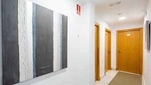 Ein Flur mit einem großen, abstrakten Gemälde an der Wand, einem Brandschutztürschild und Holztüren.