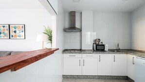 A modern kitchen with white cabinets, a granite countertop, a microwave, and a stainless steel range hood. - Terraza Catedral Olehousing 4 (Sevilla)
