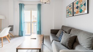 A modern living room with a grey sofa, a wooden coffee table, and a view of a balcony through a glass door. - Terraza Catedral Olehousing 4 (Sevilla)
