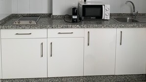 Cuina amb armaris blancs, campana extractora d'acer inoxidable, microones i taulell de granat.